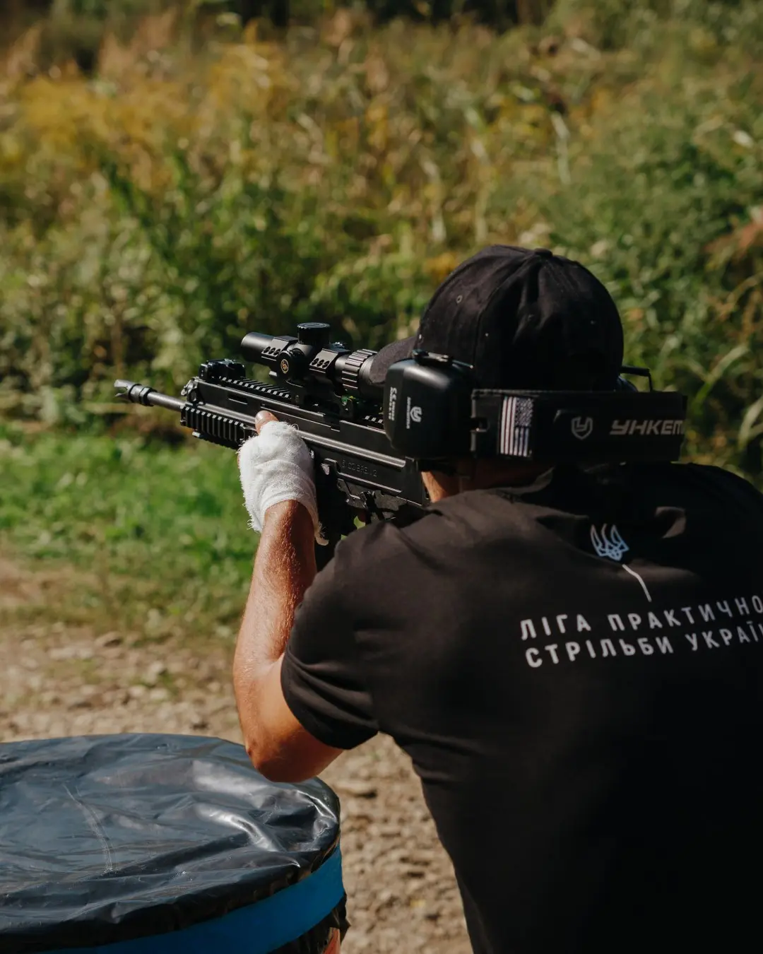 Participant in a UPSL shirt fires a carbine