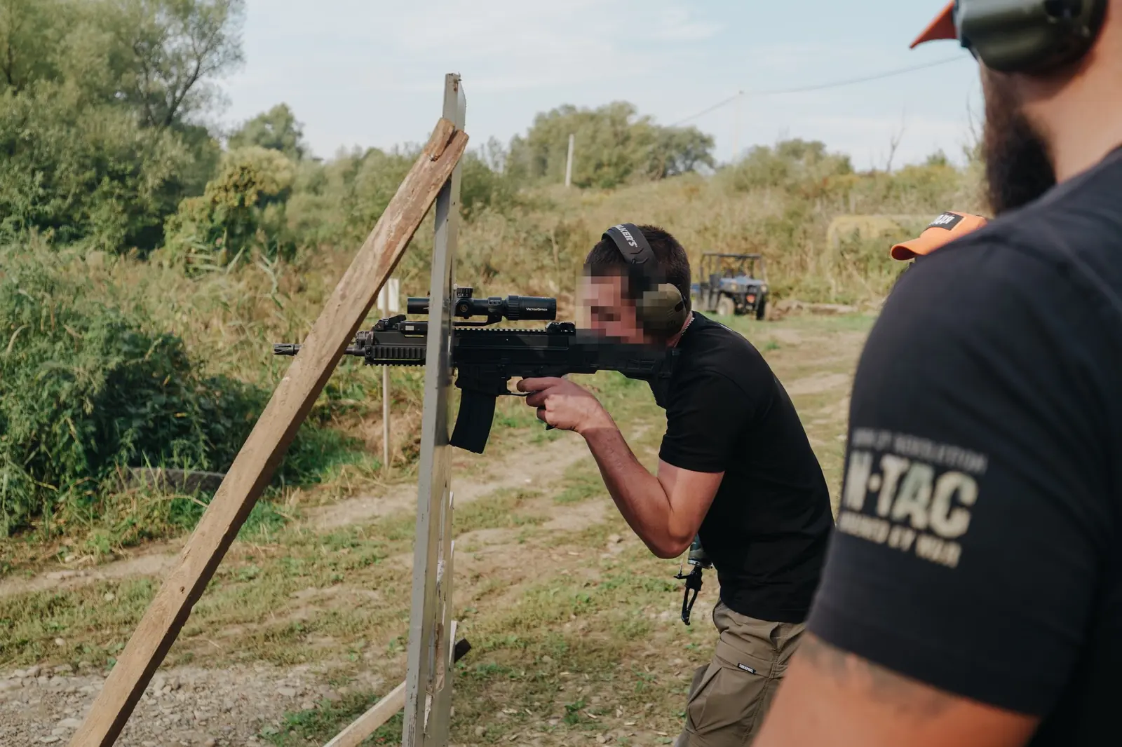 Participant fires a carbine from behind a wooden barricade